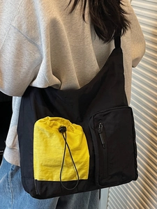 Black large capacity nylon crossbody bag with yellow drawstring pocket shown on model
