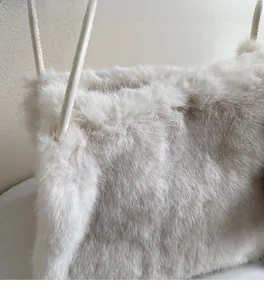 Détail d'un sac cabas en fausse fourrure crème montrant la texture douce et l'anse