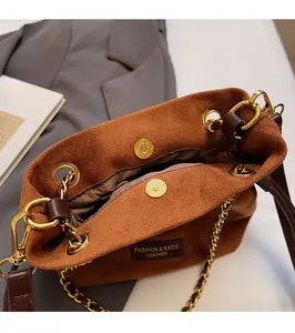 Vue détaillée du sac seau en daim marron avec fermoir magnétique et chaîne dorée