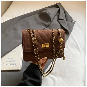 Close-up of brown suede crossbody bag with gold ball chain and quilted embroidery pattern