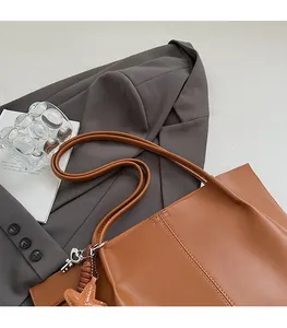 Close-up of caramel leather tote bag detailing fine stitching and star pendant