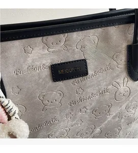 Detail of canvas tote bag featuring embossed animal patterns and black leather brand patch