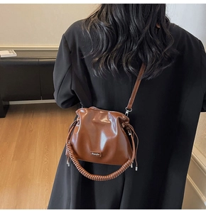 Brown glossy leather bucket bag with drawstring closure and spiral textured handle