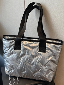 Minimalist silver metallic quilted tote bag with black fabric handles for autumn casual style