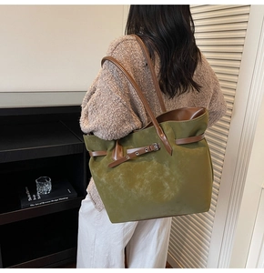 Macro detail of olive green suede tote bag with brown leather straps and metal buckle