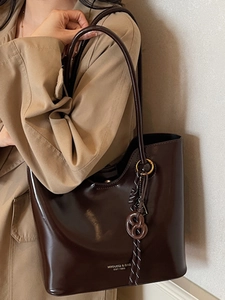 Polished brown large tote bag with twist ring and braided rope detail on models shoulder