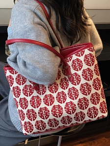 Red festive Xi pattern tote bag with leather handles shown in a lifestyle side view