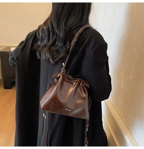 Detail of a dark brown bucket bag with twisted shoulder strap and drawstring closure