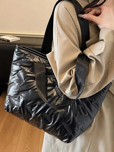 Minimalist black quilted puffer tote bag with glossy finish shown in side view styling