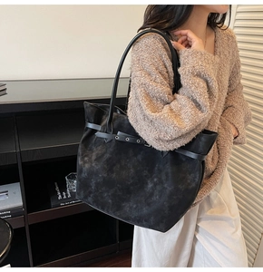 Detail of large black suede tote bag with decorative straps and fine shoulder strap