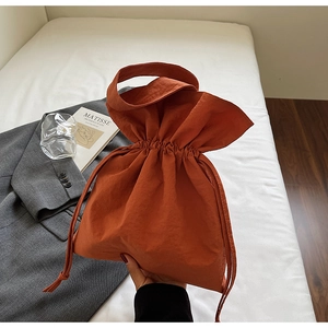 Dettaglio della borsa a secchiello color caramello con coulisse e manico in nylon