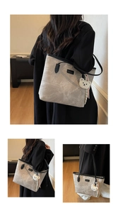Detail of light gray embossed leather tote bag with cute bear patterns and plush charm