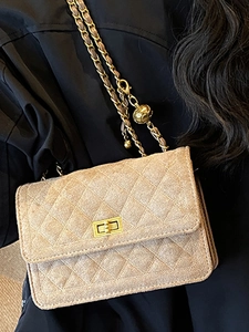 Quilted beige crossbody bag with gold chain and ball detail on black outfit