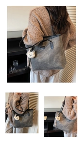 Detail of grey tote bag with embossed bear pattern and plush keychain on shoulder
