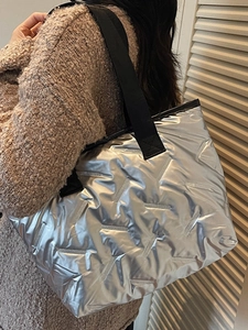 Minimalist silver quilted puffer tote bag with metallic finish and black shoulder strap