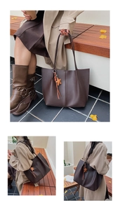 Detail of dark brown leather tote bag with orange star charm and vertical stitching on bench