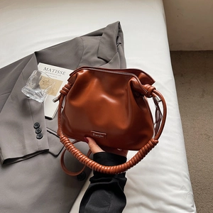 Detail of a brown pleated bucket bag featuring a unique spiral handle and metal logo plaque