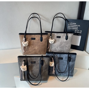 Detail view of four large tote bags featuring embossed bear patterns and plush charms