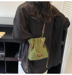 Détail du sac seau en daim vert avec cordon en cuir marron et chaîne dorée chic