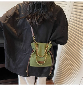 Détail du sac seau en daim vert foncé avec chaîne dorée et bandoulière sur modèle