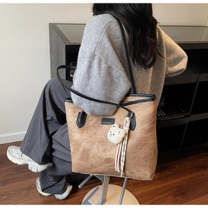 Close-up of vintage brown tote bag with bear embossing and plush charm in lifestyle setting