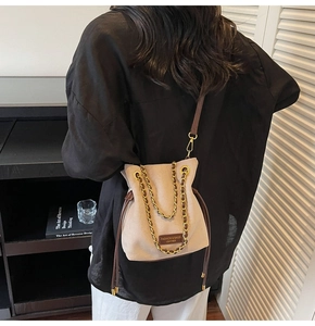 Vue détaillée du sac seau en daim beige avec cordon en cuir et bandoulière chaîne dorée
