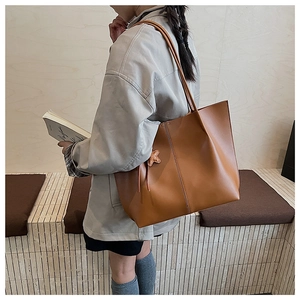 Detail view of large brown faux leather tote bag with star pendant on a model's shoulder