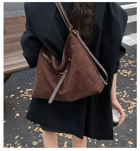 Macro shot of dark brown suede tote bag with leather strap and metal buckle detail