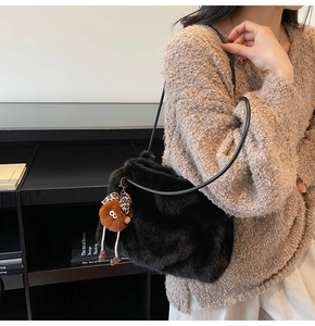 Détail d'un sac bandoulière en peluche noire avec un charm monstre marron et nœud léopard