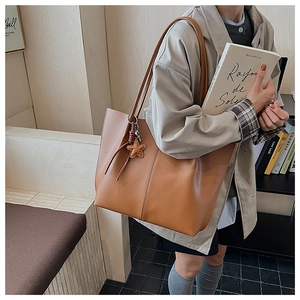 Detail of tan tote bag with vertical stitching, star charm and spacious PU leather interior