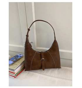 Detail of dark brown crescent bag showing premium leather texture and white contrast stitching