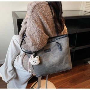 Close-up of textured grey tote bag with bear embossing and plush bear charm