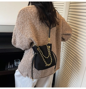 Détail du sac seau noir avec chaîne dorée et cordon porté par un mannequin