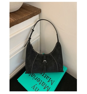 Detail view of black hobo bag with contrast stitching and silver buckle on suede texture