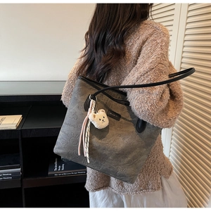 Detail of grey tote bag with embossed cartoon bear patterns and cute plush bear pendant