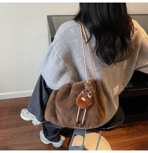 Détail d'un sac à main en peluche marron avec un charme monstre mignon sur fines lanières