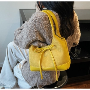 Détail du sac cabas en daim jaune avec nœud en cuir et finitions de couture