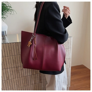 Detail view of large burgundy PU leather tote bag with star charm and woven tassel