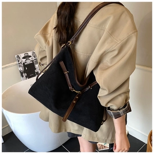 Close-up of a large black suede Hobo bag featuring brown leather straps and gold metal hardware