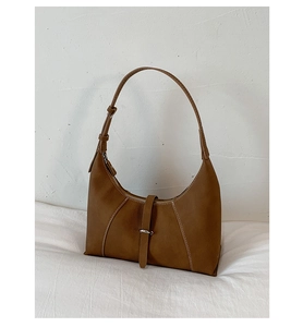 Detail showing brown pebble texture leather with white contrast stitching and metal buckle