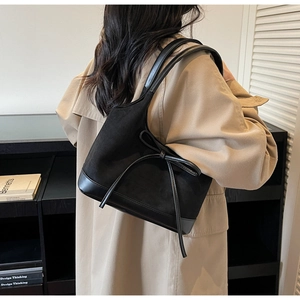 Détail du sac cabas noir avec patchwork de velours et nœud porté sur un trench-coat
