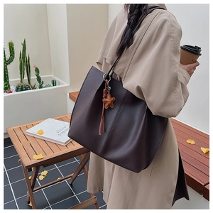 Deep brown matte leather tote bag shown in an autumn outdoor scene with star charm detail