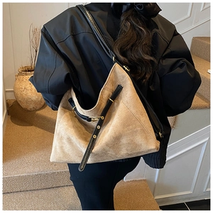 Detail of camel suede tote bag featuring black leather strap and golden metal buckle details