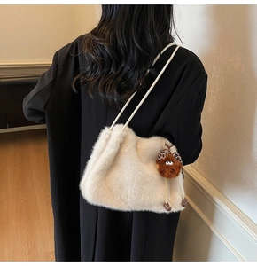 Détail du sac à main en fausse fourrure blanche avec un charmant pendentif monstre marron