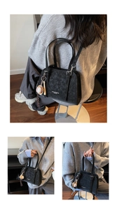 Detail view of black vintage PU leather pillow bag with silver buckles and baseball pendant