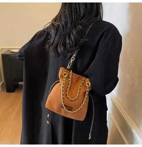 Détail du sac seau en daim marron avec bandoulière en chaîne dorée et cordon