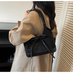 Détail du sac cabas noir avec nœud en cuir et mélange de matières en daim