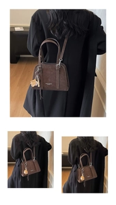 Detail of a dark coffee retro shoulder bag with suede texture and baseball glove charm