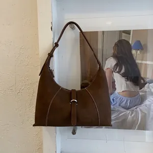 Detail of dark brown leather hobo bag featuring contrast stitching and a silver buckle strap