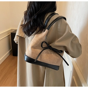 Détail du sac cabas élégant en daim beige et cuir noir avec décoration de nœud chic
